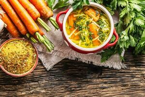 Hähnchen Suppe Brühe im ein Jahrgang Schüssel mit hausgemacht Nudeln Karotte Zwiebel Sellerie Kräuter Knoblauch und frisch Gemüse. foto