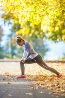 weiblich sportlich jung Frau tun Dehnen oder Erwärmen das Körper und vorbereiten zu Joggen foto