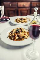 idalisch Pasta Pappardelle mit Rindfleisch Ragout auf Weiß Teller und rot Wein foto