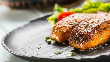 köstlich gegrillt geröstet Lachs Filets oder Steaks mit Sesam Tomaten und Grüner Salat Salat. foto