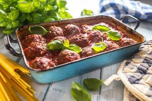 köstlich Italienisch Mahlzeit Fleisch Rindfleisch Bälle mit Pasta Spaghetti und Basilikum im Jahrgang Bräter schwenken foto