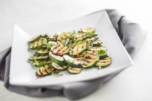 Zucchini. gegrillt Zucchini mit rot würzen auf Weiß Teller foto