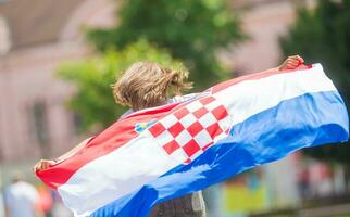 glücklich Mädchen Tourist Gehen im das Straße mit kroatisch Flagge foto
