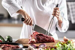 Fachmann Besteck benutzt durch ein Koch zu Schnitt rot Fleisch auf ein Hacken Tafel foto