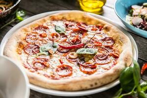 Pizza Salami diavola mit rot Zwiebel Basilikum und Chili Pfeffer foto