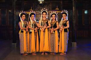 ein Gruppe von javanisch Tänzer Stehen mit ihr freunde während tragen Gelb Kostüme und Schals foto