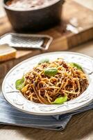 Italienisch Pasta Spaghetti Bolognese serviert auf Weiß Teller mit Parmesan Käse und Basilikum foto