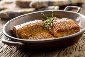 Lachs. zwei saftig Lachs Steaks im braten schwenken mit Kraut Dekoration auf rustikal Eiche Tabelle foto