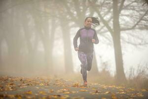 sportlich Frau Laufen im nebelig Herbst Natur foto