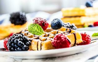 frisch Waffeln mit Schokolade Sirup Beeren Zucker Pulver Ameise Minze Blätter. foto