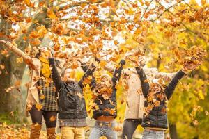 Familie Spaß draußen im das Herbst durch werfen gefallen Blätter oben im das Luft foto