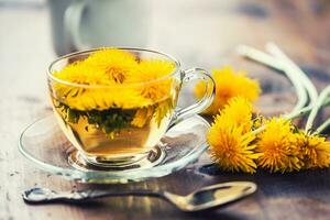 Tasse von Löwenzahn Tee auf rustikal hölzern Tabelle foto