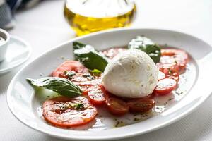 Caprese Salat von Mozzarella Tomaten Basilikum Olive Öl ein Gewürze foto