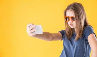 Porträt von verrückt Teen Mädchen mit retro Brille Herstellung Selfie Über Gelb Hintergrund foto