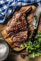 frisch gegrillt Tomahawk Steak auf Schiefer Teller mit Salz- Pfeffer Rosmarin und Petersilie Kräuter. geschnitten Stücke von saftig Rindfleisch Steak foto