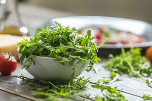 frisch Rucola Salat im Weiß Gericht auf hölzern Tabelle foto