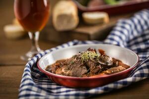 braten wild Eber mit Karotte Pilze, Stangenbrot und Entwurf Bier foto