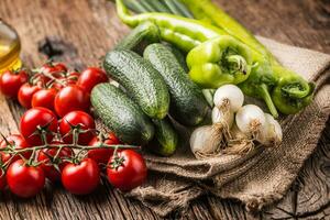 frisch Gemüse Zwiebel Gurke Pfeffer und Tomaten auf rustikal Eiche Tabelle foto