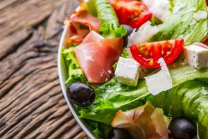 Salat. frisch Sommer- Grüner Salat Salat.gesund Mittelmeer Salat Oliven Tomaten Parmesan Käse und Prosciutto. foto