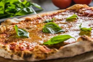 Italienisch traditionell Pizza Margarita auf runden hölzern Tafel mit Basilikum Tomaten und Parmesan foto