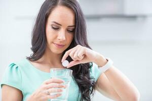 jung Frau mit Magnesia Brausetabletten Tablette und Glas von rein oder Mineral Wasser foto