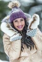 modisch weiblich Modell- trägt flauschige Handschuhe, glänzend Jacke und violett pom pom Hut zum Winter foto