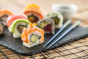 einstellen von rollen Sushi mit Essstäbchen auf Schiefer Tafel foto