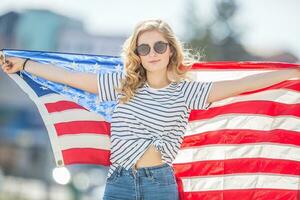 attraktiv glücklich jung Mädchen mit das Flagge von das vereinigt Zustände von Amerika foto