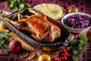 Weihnachten braten Gans mit rot Kohl, Kartoffel Knödel im ein Original Backen Gericht auf das festlich Tabelle foto