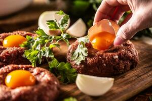 Damen Hand Portion Ei Eigelb auf ein Rindfleisch Steak Tartar mit Kräuter und Zwiebel foto