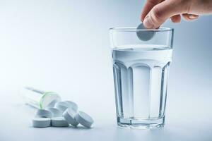 Magnesium Tabletten und Tasse von klar Wasser auf Blau Weiß Hintergrund foto