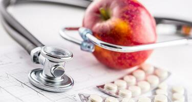 Stethoskop Apfel und Tabletten auf Weiß Hintergrund foto