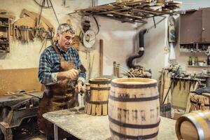 Zuhause Werkstatt von ein Handwerker Wer baut hölzern Fässer zum Whiskey oder Wein mit seine besitzen Hände foto