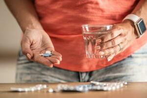 Tabletten Blasen, Tabletten im das Hand von ein Frau und ein Glas von Wasser foto