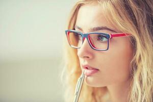 Universität Schüler Mädchen nachdenklich mit Stift auf ihr Lippen. Porträt von Denken Frau mit Brille. foto