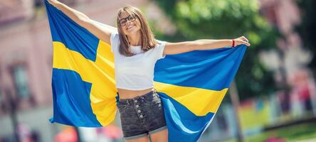 glücklich Mädchen Tourist Gehen im das Straße mit Schweden Flagge foto