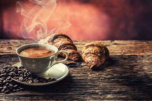 Kaffee. Tasse von Kaffee Croissants und Kaffee Bohnen. Jahrgang Tasse und alt Eiche Tabelle foto