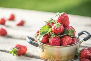 frisch reif Erdbeeren im Jahrgang Küche Topf auf alt Garten Tabelle foto