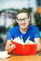 ein Mann im Brille Sitzung beim ein Tabelle mit ein Tasse von Kaffee foto