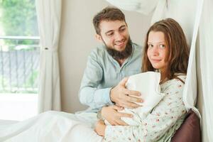 ein Mann und Frau sind halten ein Baby foto