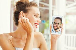 ein Frau halten oben ein Telefon mit ein Mann auf es foto