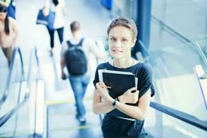 ein Frau ist Stehen auf ein Rolltreppe mit ihr Laptop foto