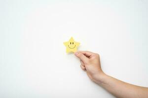 Hand halten Gelb Star glücklich Lächeln Gesicht, gut Feedback Bewertung und positiv Kunde Rezension, Erfahrung, Befriedigung Umfrage, mental Gesundheit Bewertung, Kompliment. foto