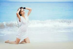 ein Frau im ein Weiß Kleid Sitzung auf das Strand foto