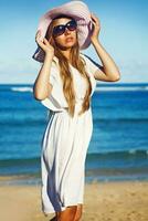 ein Frau im ein Weiß Kleid und Hut auf das Strand foto