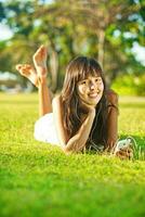 asiatisch Frau Hören zu Musik- auf ihr Zelle Telefon im das Park foto