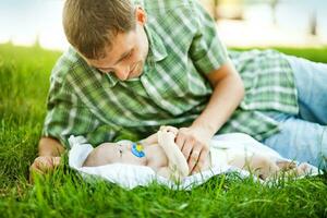 ein Mann Verlegung auf das Gras mit seine Baby foto