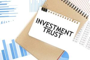 Text Investition Vertrauen auf Weiß Papier Blatt und braun Papier Notizblock auf das Tabelle mit Diagramm. Geschäft Konzept foto