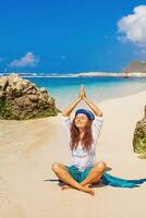 ein Frau Sitzung auf das Strand tun Yoga foto