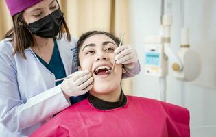 Vorderseite Aussicht von Zahnarzt Überprüfung geduldig mit Bagger und Dental Spiegel, Zahnarzt Überprüfung geduldig mit Bagger und Dental Spiegel, geduldig überprüft durch Zahnarzt, Zahnarzt tun Dental Untersuchung foto